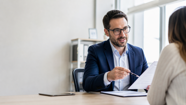 Insurance agent reviewing policy paperwork with a client in an office.